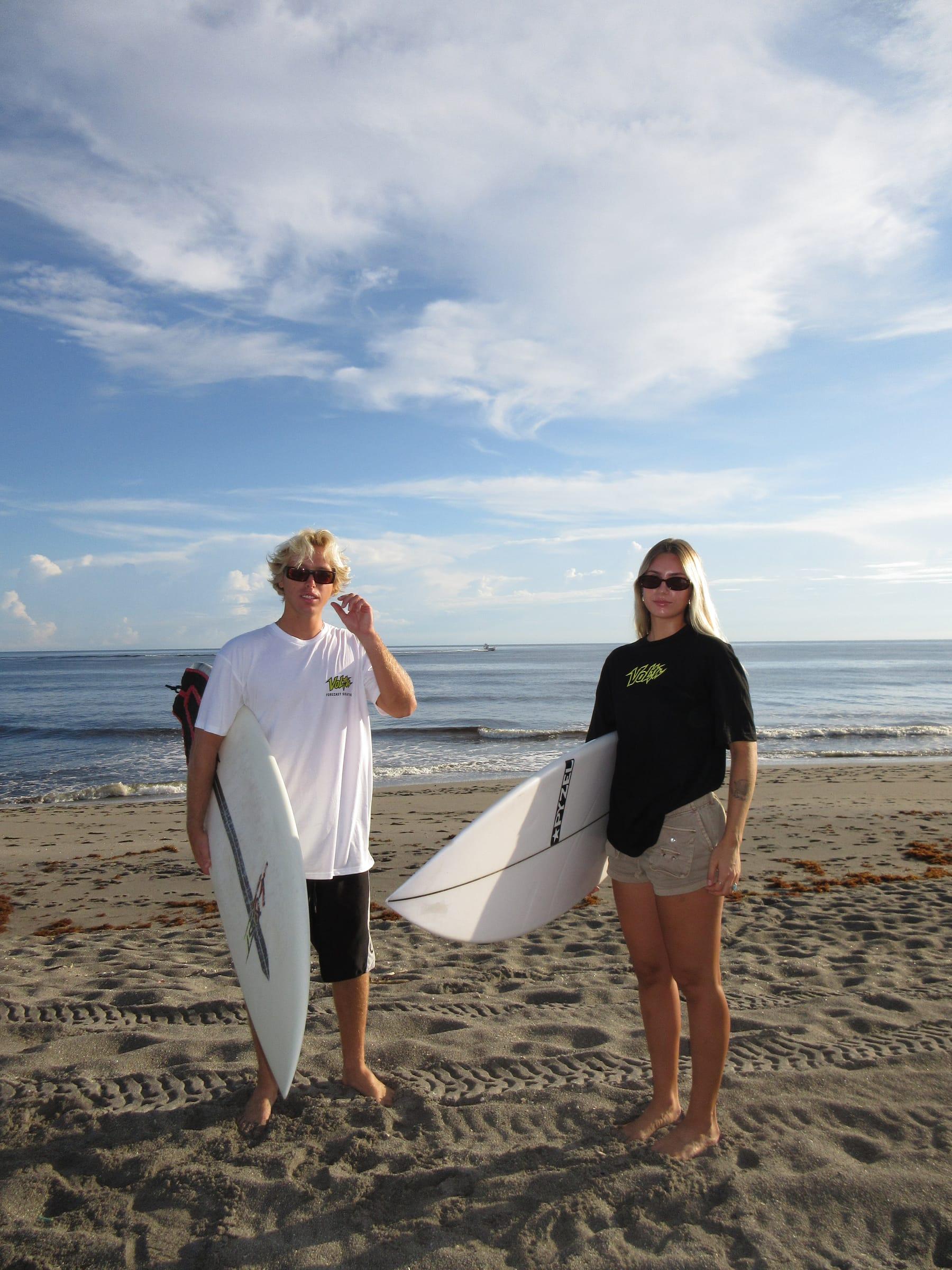 Two surfers on the beach in Volta tees